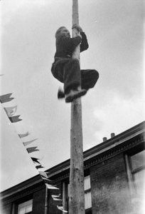 818822 Afbeelding van een paalklimmer tijdens een bevrijdingsfeest in (vermoedelijk) de wijk Wittevrouwen te Utrecht.